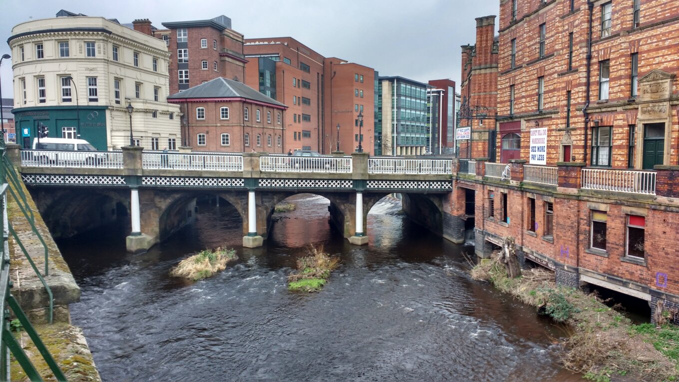 A bridge over a river surrounded by brick buildings.
