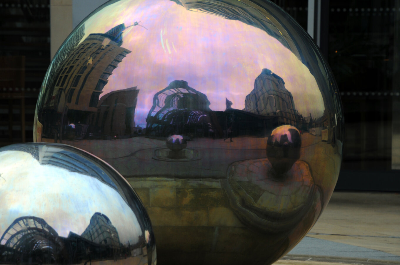 Two giant steel balls with the reflection of the Winter Garden and other buildings.