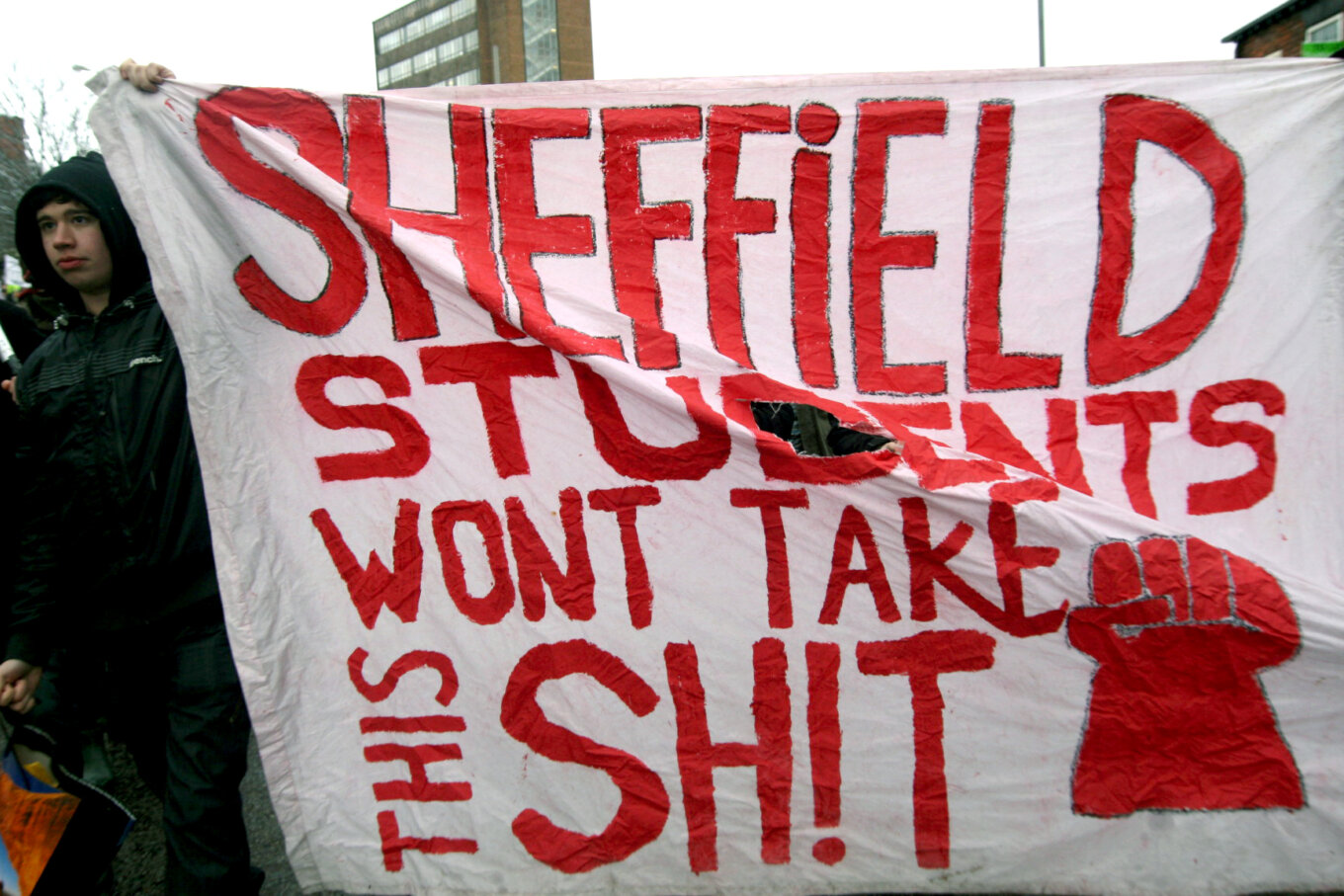 A hand-painted banner that reads Sheffield students won't take this shit in red with a red fist.