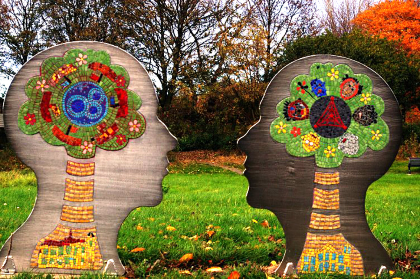 Two faces, in profile, made out of wood, with brightly coloured decoration where the brain would be.