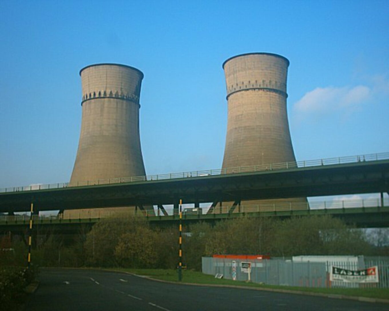 Two cooling towers in front of a blue sky.