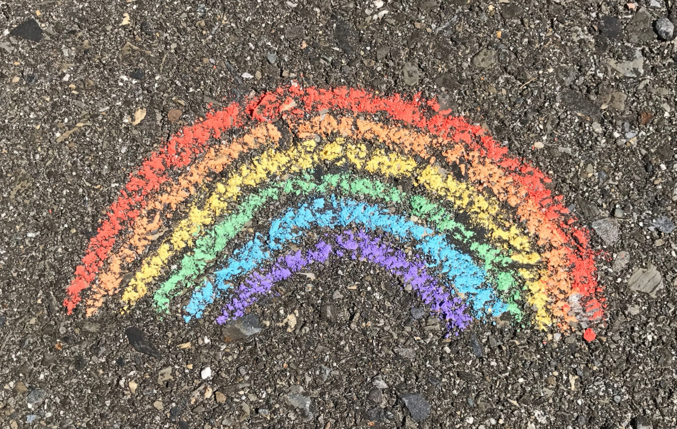 A hand-drawn chalk rainbow on a dark background