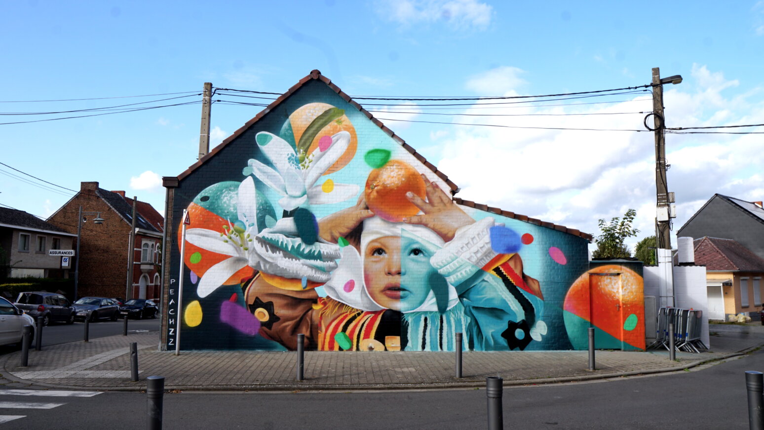 A brightly coloured painting on the side of a building featuring a child and oranges.
