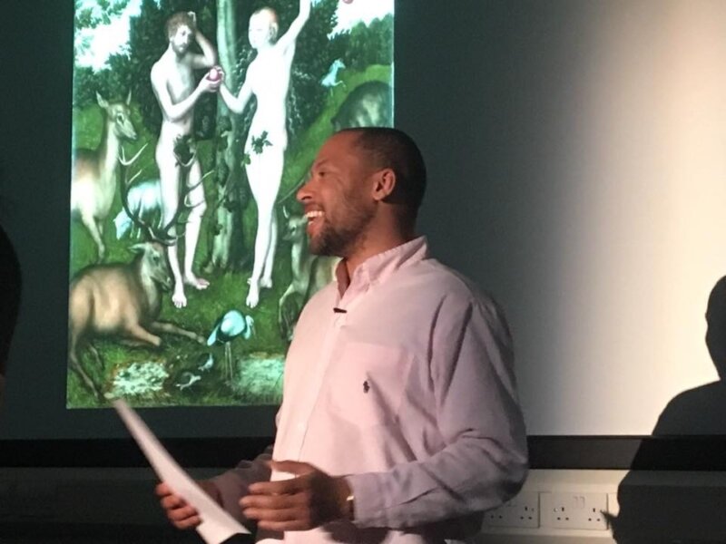 Dean Atta performing 'Two Black Boys in Paradise' at The Courtauld, in front of a screen projection of Lucas Cranach the Elder’s ‘Adam and Eve’, 1526.